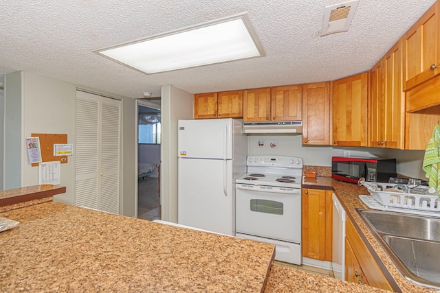 kitchen with a textured ceiling, sink, and white appliances