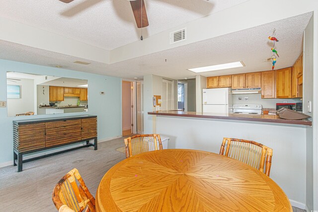 dining space with a textured ceiling, light hardwood / wood-style floors, and ceiling fan