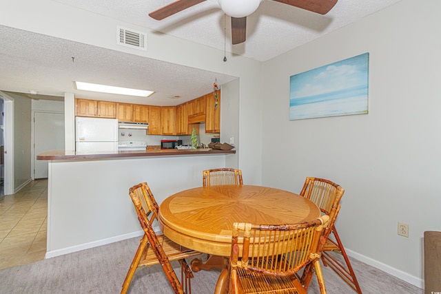 dining area with a textured ceiling, light tile patterned floors, and ceiling fan