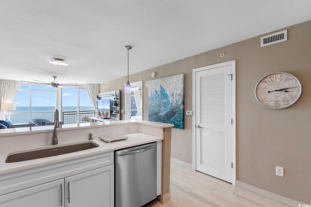 kitchen with sink, stainless steel dishwasher, decorative light fixtures, light hardwood / wood-style floors, and a water view