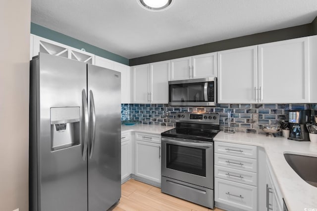 kitchen with appliances with stainless steel finishes, light wood-type flooring, and white cabinetry