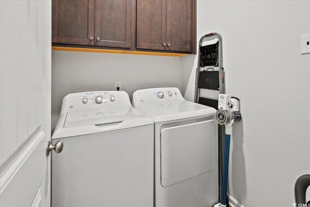 laundry room featuring separate washer and dryer and cabinets