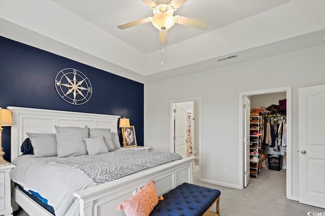 bedroom featuring a walk in closet, light colored carpet, baseboards, visible vents, and a closet