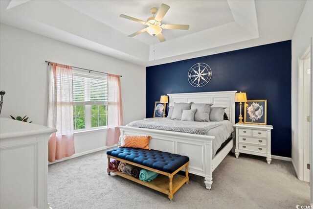 carpeted bedroom with a tray ceiling and ceiling fan