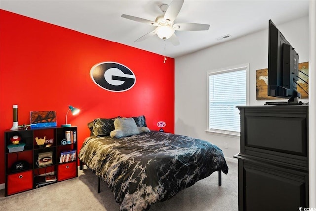 carpeted bedroom with baseboards, ceiling fan, visible vents, and an accent wall