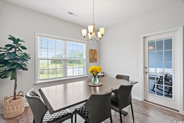 dining room featuring baseboards, visible vents, wood finished floors, and a chandelier