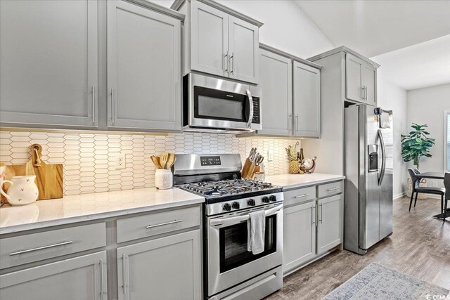 kitchen with gray cabinetry, light wood-type flooring, and appliances with stainless steel finishes