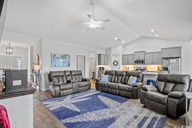 living room featuring ceiling fan with notable chandelier, high vaulted ceiling, and hardwood / wood-style flooring