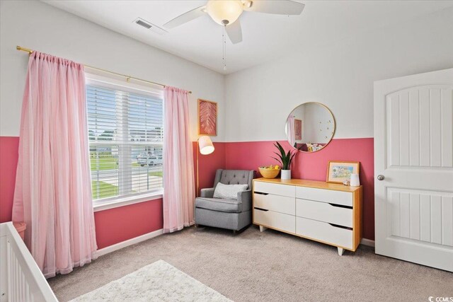 bedroom with ceiling fan, a nursery area, and light carpet