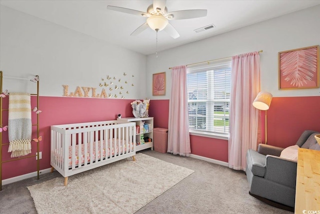 carpeted bedroom with ceiling fan and a nursery area