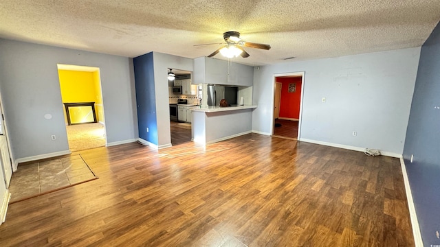 unfurnished living room featuring ceiling fan, dark wood-type flooring, and a textured ceiling