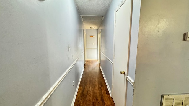 hall featuring a textured ceiling and dark hardwood / wood-style floors