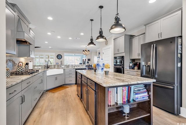 kitchen featuring hanging light fixtures, sink, stainless steel appliances, a center island, and light hardwood / wood-style floors