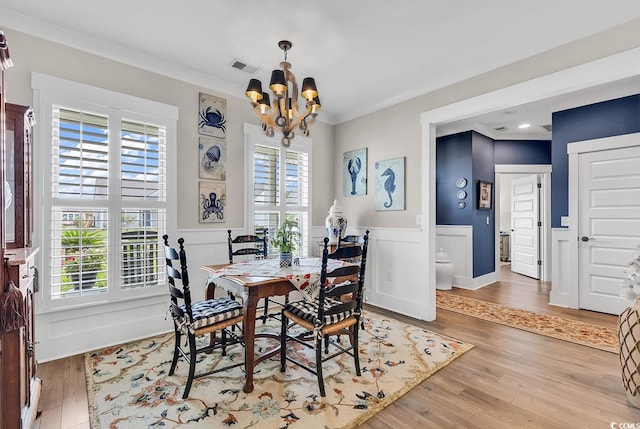 dining space featuring a notable chandelier, a wealth of natural light, hardwood / wood-style floors, and crown molding