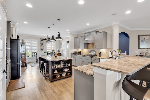 kitchen featuring pendant lighting, kitchen peninsula, gray cabinets, a breakfast bar, and light wood-type flooring