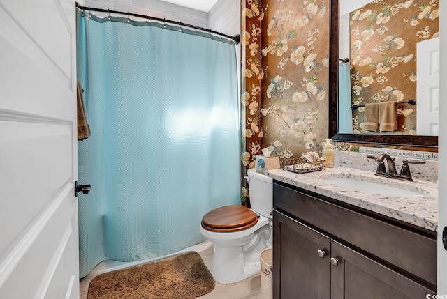 bathroom with walk in shower, vanity, and toilet