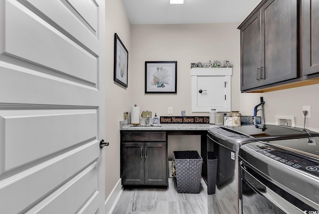 laundry room with light wood-type flooring, sink, independent washer and dryer, and cabinets