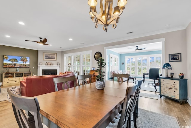 dining space with ceiling fan with notable chandelier, light wood-type flooring, and ornamental molding