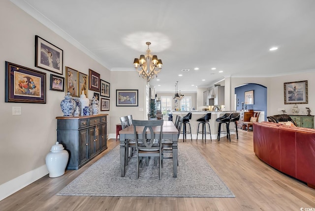 dining area featuring light hardwood / wood-style floors, ornamental molding, and an inviting chandelier