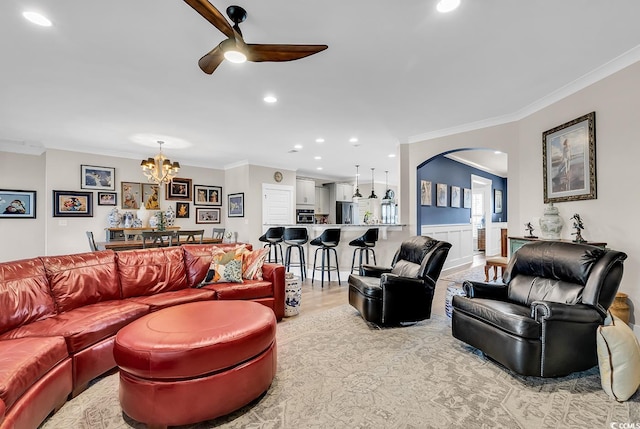 living room with ceiling fan with notable chandelier, light hardwood / wood-style flooring, and crown molding