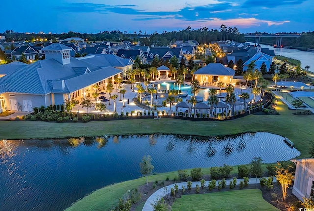 aerial view at dusk featuring a water view