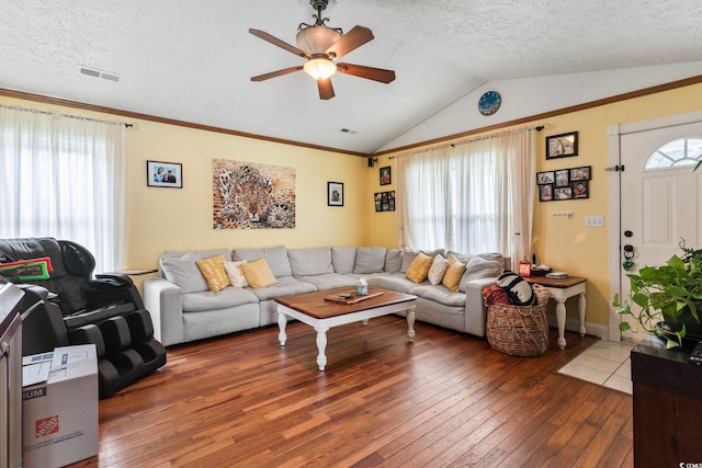 living room with a textured ceiling, vaulted ceiling, ceiling fan, and dark wood-type flooring