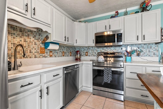 kitchen featuring sink, ornamental molding, a textured ceiling, white cabinetry, and stainless steel appliances