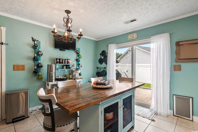 dining area featuring a notable chandelier, a textured ceiling, crown molding, and light tile patterned floors