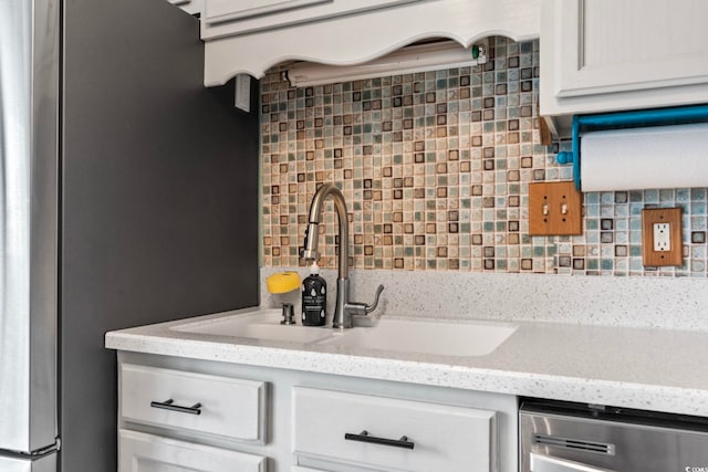 kitchen featuring decorative backsplash, white cabinetry, light stone counters, dishwasher, and sink