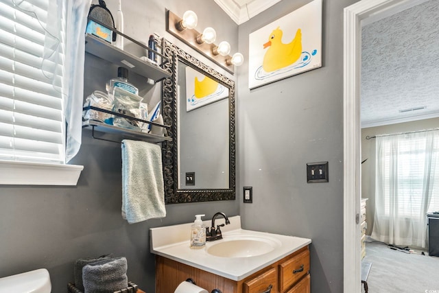 bathroom with a textured ceiling, crown molding, vanity, and toilet