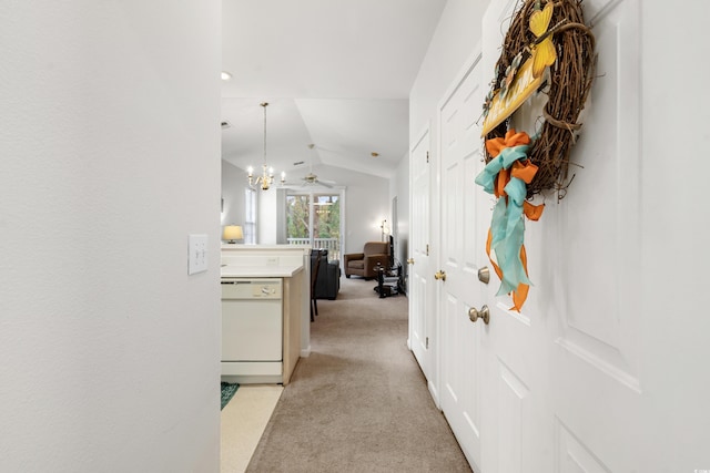 hall featuring light colored carpet, a notable chandelier, and vaulted ceiling