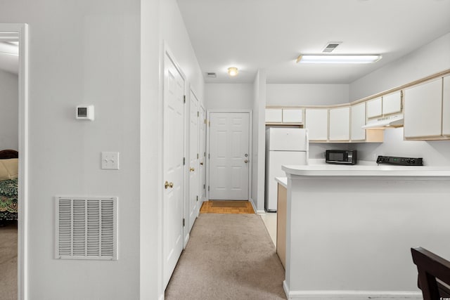 kitchen featuring light carpet, white cabinetry, kitchen peninsula, and white fridge