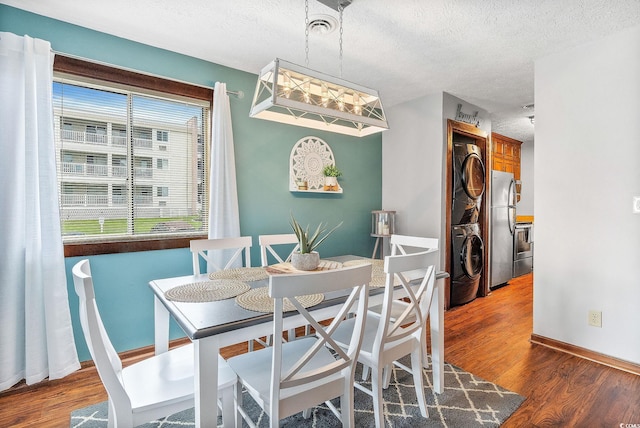 dining area featuring a textured ceiling, stacked washer and dryer, and dark hardwood / wood-style flooring