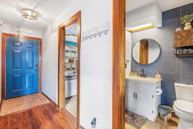 foyer entrance with a textured ceiling, sink, and light hardwood / wood-style flooring