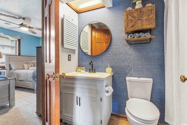 bathroom with ceiling fan, vanity, toilet, and a textured ceiling