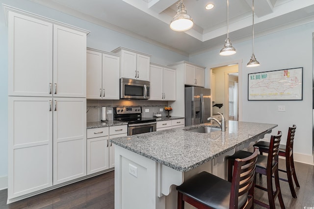 kitchen featuring a breakfast bar, a sink, appliances with stainless steel finishes, and dark wood-style flooring