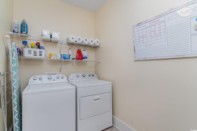 clothes washing area with washing machine and clothes dryer, baseboards, and laundry area