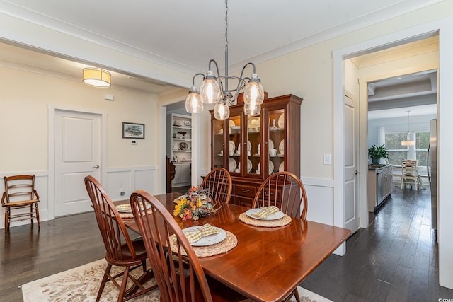 dining space with wainscoting, an inviting chandelier, dark wood-type flooring, and a decorative wall