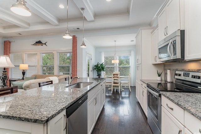 kitchen featuring white cabinets, a kitchen island with sink, beam ceiling, a sink, and appliances with stainless steel finishes