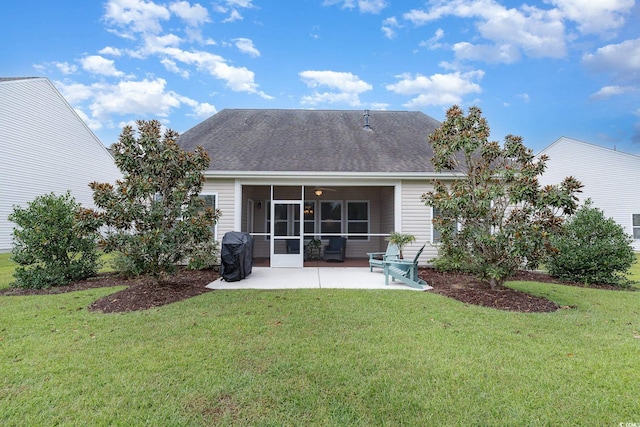rear view of house with a lawn, a sunroom, roof with shingles, and a patio
