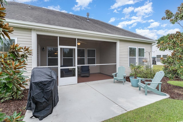 rear view of property with roof with shingles, a sunroom, and a patio area