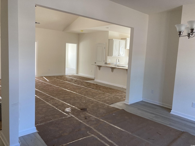 unfurnished living room featuring sink and a notable chandelier