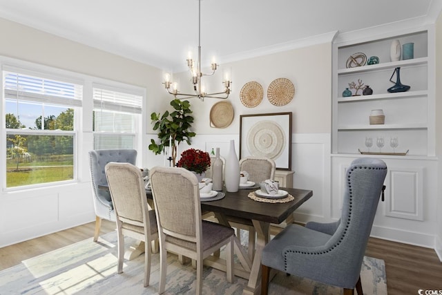 dining area featuring hardwood / wood-style flooring, crown molding, a chandelier, and built in shelves