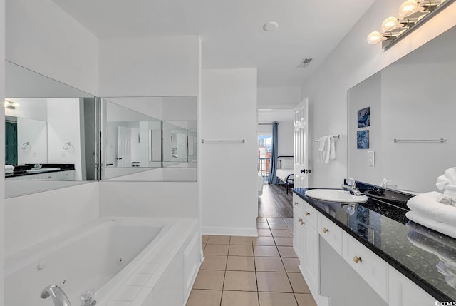 bathroom with a relaxing tiled tub, tile patterned flooring, and vanity