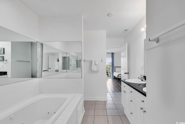 bathroom featuring tiled tub, vanity, and tile patterned floors