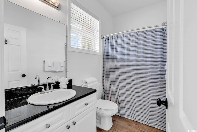 bathroom with walk in shower, hardwood / wood-style flooring, vanity, and toilet