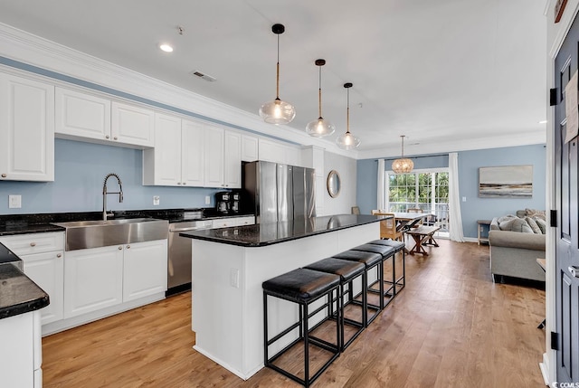 kitchen featuring stainless steel appliances, sink, white cabinetry, and a kitchen island