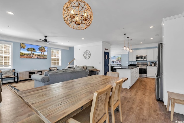 dining room featuring ceiling fan with notable chandelier, light wood-type flooring, and crown molding