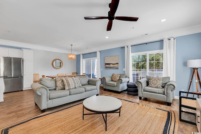 living room with ceiling fan, light hardwood / wood-style flooring, and crown molding