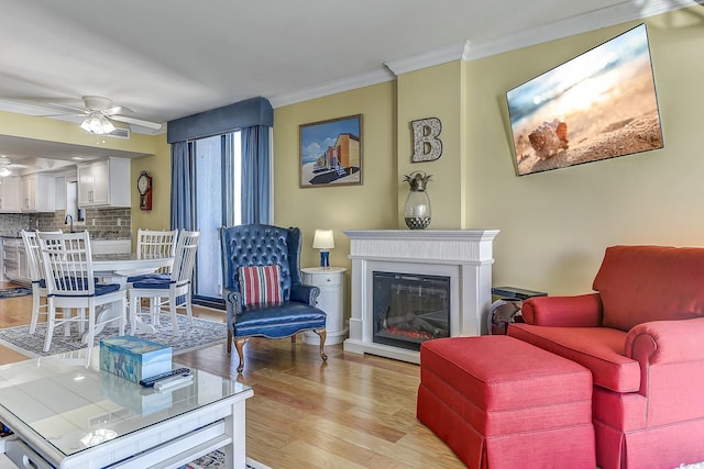 living room with ceiling fan, light wood-type flooring, and crown molding